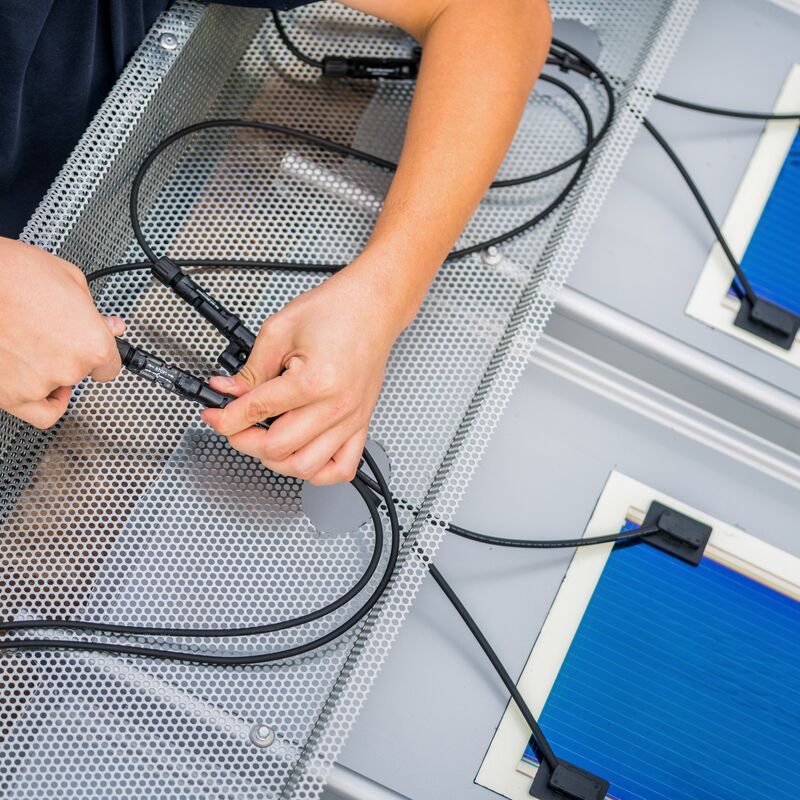 Fachkraft installiert ein Photovoltaik-Modul auf dem Dach eines Gebäudes - Teil der Gebäudehülle für nachhaltige Energiegewinnung