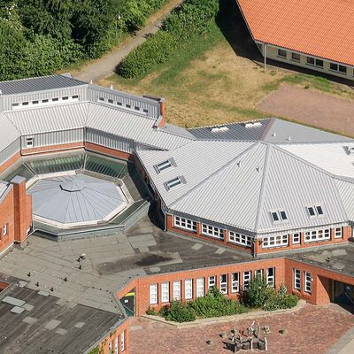 Dach eines großen, verwinkelten Schulgebäudes mit verlegtem Zambelli RIB-ROOF 465 Metalldachsystem - langlebige und elegante Dachlösung