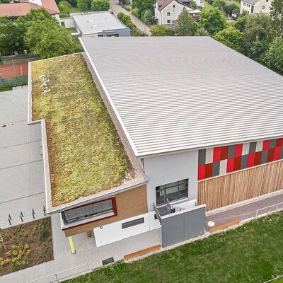 Ansicht eines großen Gebäudes mit verlegtem Zambelli RIB-ROOF Evolution Metalldachsystem in Kombination mit Zambelli Gründachsystem - für eine moderne, nachhaltige und langlebige Dachlösung