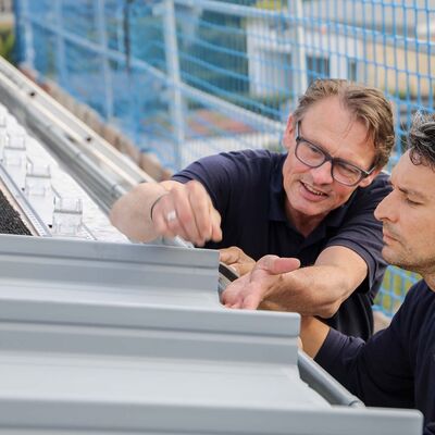 Zambelli Monteure auf dem Dach eines Wohnhauses, auf dem das Zambelli RIB-ROOF Akustikdach verlegt wird